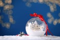 Decorative snow globe with red ribbon against blurred festive lights, closeup Royalty Free Stock Photo