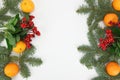 Decorative spruce branches laid out on the left and right edges of the image, on top of them are tangerines and lingonberries