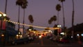 Decorative staring garland lights, palm trees silhouettes, evening sky. Blurred Background. Street decorated with lamps in Royalty Free Stock Photo