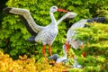 Decorative statue of a family of storks in the garden on a background of green leaves