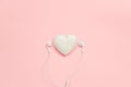 Decorative textile volume heart and white headphones on pink background. Concept listen to your heart or love of music. Top view Royalty Free Stock Photo