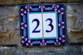 Decorative tile with the number 23, set on a stone wall Royalty Free Stock Photo