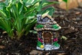 Decorative tiny gnome house is among flowers in the garden