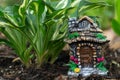 Decorative tiny gnome house is among flowers in the garden