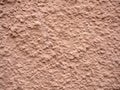 Decorative uneven plaster painted in pink-beige color. Abstract background Royalty Free Stock Photo