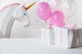 Decorative unicorn and balloons with gifts on white brick