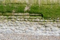 Decorative weathered old wall by the sea in Normandy, stone in part concrete, section, with algae and moss, copy space, space for