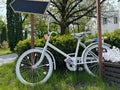 A bicycle with a flower basket at the entrance to the park. Decorative white bicycle for decoration in the garden. Decor with Royalty Free Stock Photo