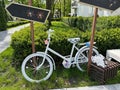 A bicycle with a flower basket at the entrance to the park. Decorative white bicycle for decoration in the garden. Decor with Royalty Free Stock Photo