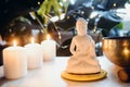 Decorative white Buddha statuette , burning candles and singing bowl with green monstera plant on the background Royalty Free Stock Photo