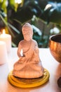 Decorative white Buddha statuette , burning candles and singing bowl with green monstera plant on the background Royalty Free Stock Photo