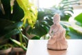 Decorative white Buddha statuette with candles and green monstera plant on the background. Meditation and relaxation Royalty Free Stock Photo
