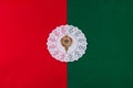 Decorative white circle doily with gold bauble flat lay on red and green background. Concept for Christmas invitation