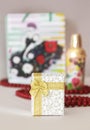 Decorative white gift box with a yellow bow on the background of a parfume and red beads Royalty Free Stock Photo