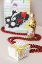 Decorative white gift box with a yellow bow on the background of a parfume and red beads Royalty Free Stock Photo