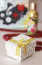 Decorative white gift box with a yellow bow on the background of a parfume and red beads Royalty Free Stock Photo
