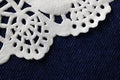 DECORATIVE WHITE PAPER DOILY ON BLUE DENIM CLOTH BACKGROUND