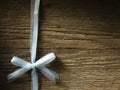 Decorative white ribbon and bow over wooden background