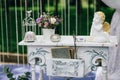 Decorative white vintage table at the wedding ceremony, candle-decorated books with flowers and ceramic angles and Royalty Free Stock Photo
