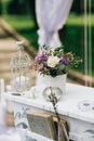 Decorative white vintage table for the wedding ceremony, decorated with a candle in a cage with a bouquet of flowers Royalty Free Stock Photo