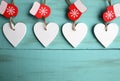 Decorative white wooden Christmas hearts and red mittens on blue wooden background with copy space. Royalty Free Stock Photo