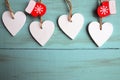 Decorative white wooden Christmas hearts and red mittens on blue wooden background with copy space. Royalty Free Stock Photo