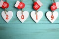 Decorative white wooden Christmas hearts and red mittens with 2019 numbers on blue wooden background with copy space. Royalty Free Stock Photo