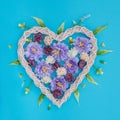 Decorative wicker heart with artificial flowers on a blue background Royalty Free Stock Photo