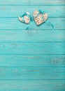 Decorative wicker heart of gray color with a blue ribbon on a wooden background.