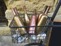 Decorative wine bottles painted in gold and bronze in a bicycle basket