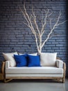 Decorative wooden branches and wood cut composition. White sofa with blue cushions near brick wall. Unique interior design