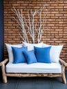 Decorative wooden branches and wood cut composition. White sofa with blue cushions near brick wall. Unique interior design