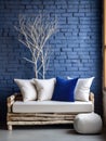 Decorative wooden branches and wood cut composition. White sofa with blue cushions near brick wall. Unique interior design