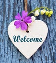 Decorative Wooden Heart With Spring Flowers And Text Welcome On Blue Old Wood Background.