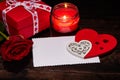 Decorative wooden red hearts, gift box, rose and blank sheet for greeting card on dark wooden background. Valentine`s Day card