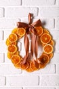 Decorative wreath made with dry oranges and ribbon hanging on white brick wall Royalty Free Stock Photo