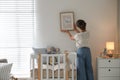 Decorator hanging picture on wall in baby room