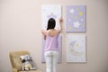 Decorator hanging picture on pink wall. Children`s room interior design