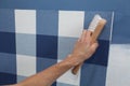 Decorator hanging wallpaper with work tool in motion