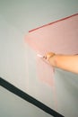 Decorator's hand painting wall with paint brush. Painting wall with pink peach colour Royalty Free Stock Photo