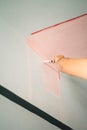 Decorator's hand painting wall with paint brush. Painting wall with pink peach colour Royalty Free Stock Photo