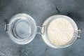 Decorticated sesame seeds, in glass jar, on gray stone background, top view flat lay