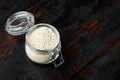 Decorticated sesame seeds, in glass jar, on old dark wooden table background , with copyspace and space for text