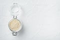 Decorticated sesame seeds, in glass jar, on white stone background, top view flat lay , with copyspace and space for text