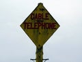 A decrepit warning post advising a telephone cable is underground Royalty Free Stock Photo