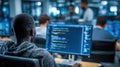 A dedicated black male software developer collaborates in a modern office setting, focused on coding alongside a diverse Royalty Free Stock Photo