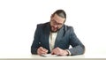 Dedicated businessman writing in notebook beside laptop at work