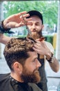 Dedicated hairstylist using scissors and comb while giving a coo