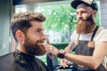 Dedicated hairstylist using scissors and comb while giving a coo