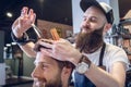 Dedicated hairstylist using scissors and comb while giving a cool haircut